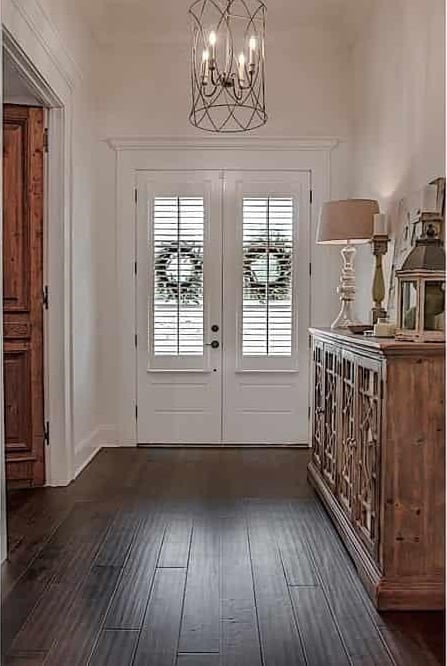 The foyer has a cylindrical candle pendant and a wooden console table graced with intricate carvings.