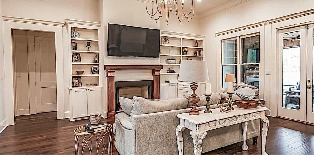 Great room with a gray sofa, a TV, and a fireplace flanked by built-in shelves and base cabinets.