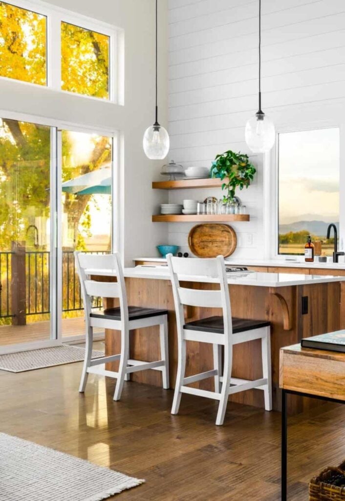 A couple of glass pendants and cushioned counter chairs complement the kitchen island.