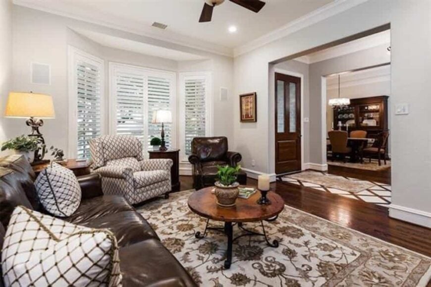 The study has leather and patterned seats paired with a round coffee table sitting on a floral area rug.