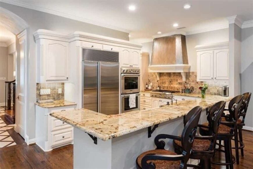 Kitchen with stainless steel appliances, white cabinetry, and a large center island with a raised eating bar.