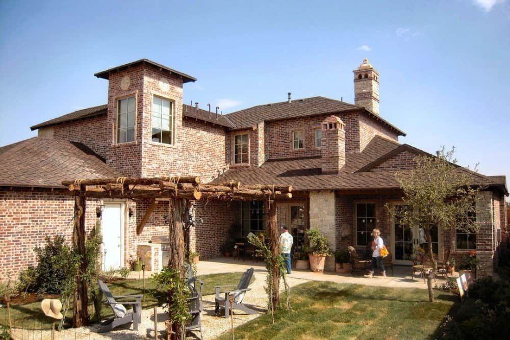 View of the house from the backyard showcasing its trellis porch, summer kitchen, and covered lanais.