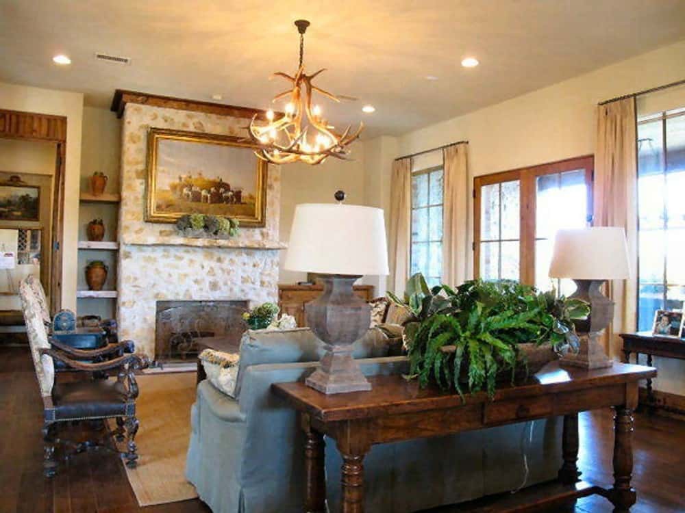 Family room with leather and fabric seats, an antler chandelier, and a fireplace adorned with framed artwork.