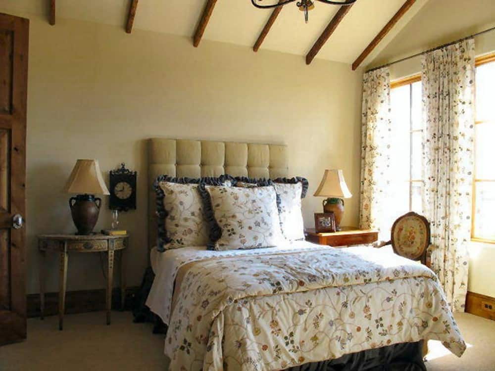 The beamed ceiling in the primary suite is mirrored in the guest bedroom.