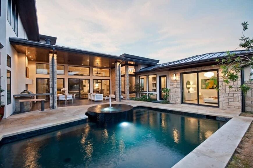Rear exterior view showcasing its covered porch and a swimming pool integrated with a built-in spa.