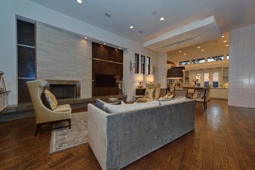 An open layout view of the great room, dining area, and kitchen illuminated with warm recessed ceiling lights.