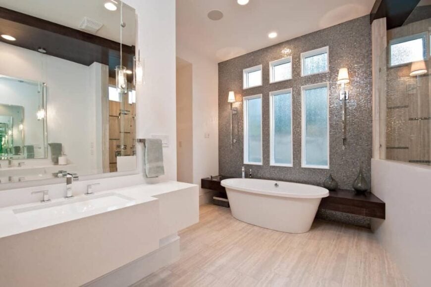 The primary bathroom has a large vanity, a walk-in shower, and a freestanding tub placed against the tall windows.