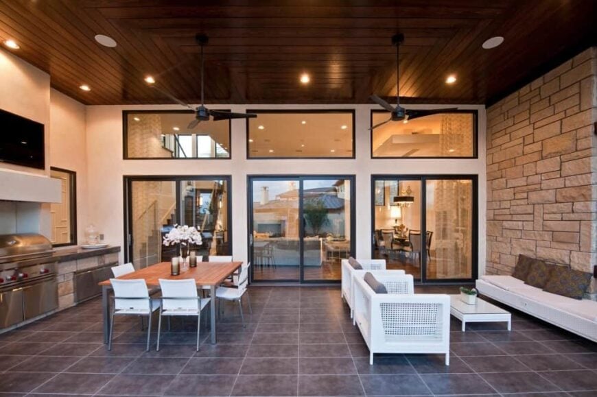 The covered porch is filled with white wicker seats, an outdoor dining, and a summer kitchen.