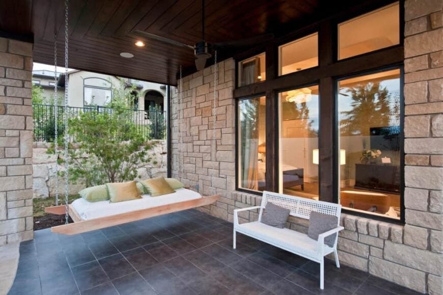 Covered pavilion with a white bench and a porch swing topped with green pillows.