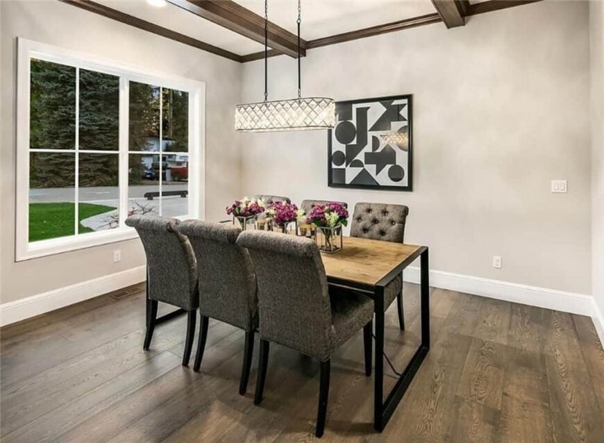 The formal dining room has a rectangular dining set and a linear chandelier that hangs from the beamed ceiling.