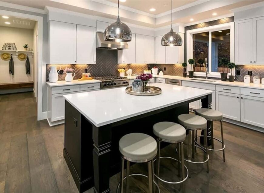 Kitchen with quartz countertops, white cabinetry, a breakfast island, and gray tile backsplash arranged in a herringbone pattern.