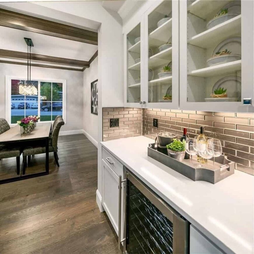 Built-in bar near the dining area with glass-front cabinets, subway tile backsplash, and a wine fridge.
