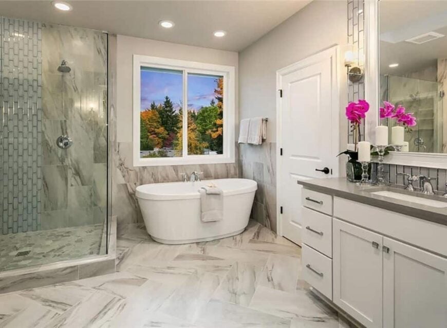 Primary bathroom with white vanity, a walk-in shower, and a freestanding tub over marble tile flooring.
