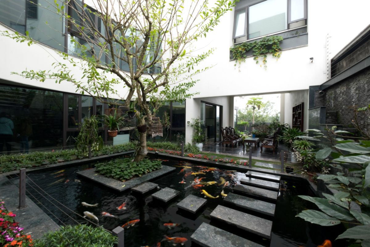 The house facade has an open space in the center that highlights a pond with a variety of fish.