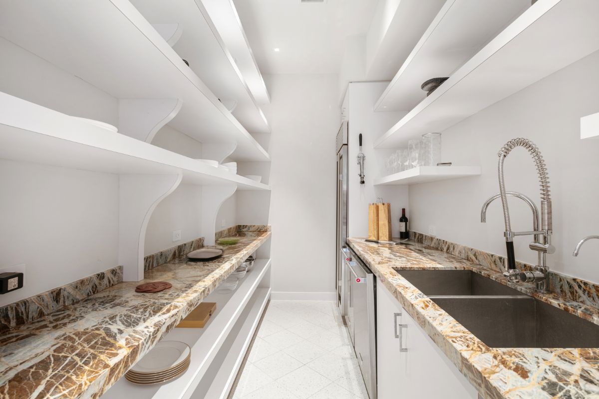 Marble-topped pantry and white painted wooden shelves.
