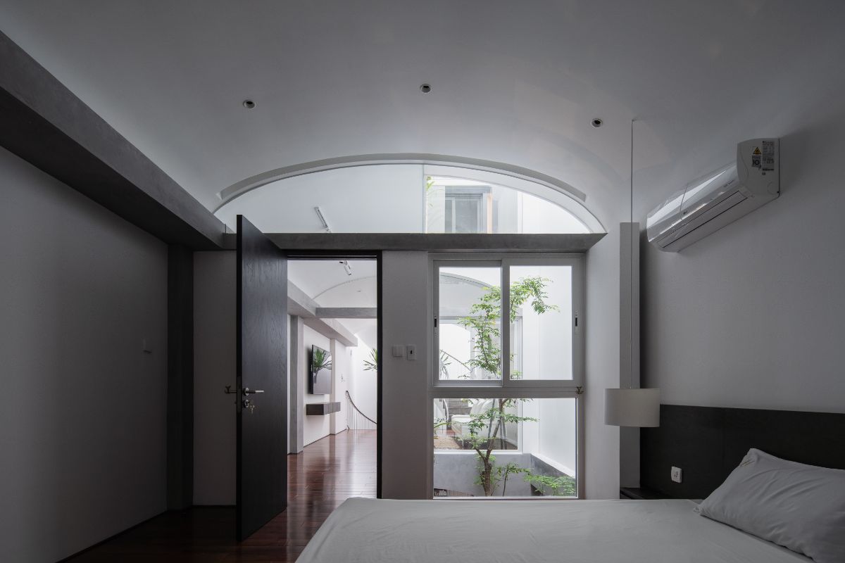 A bedroom with dome-shape ceiling, concrete walling and glass windows.