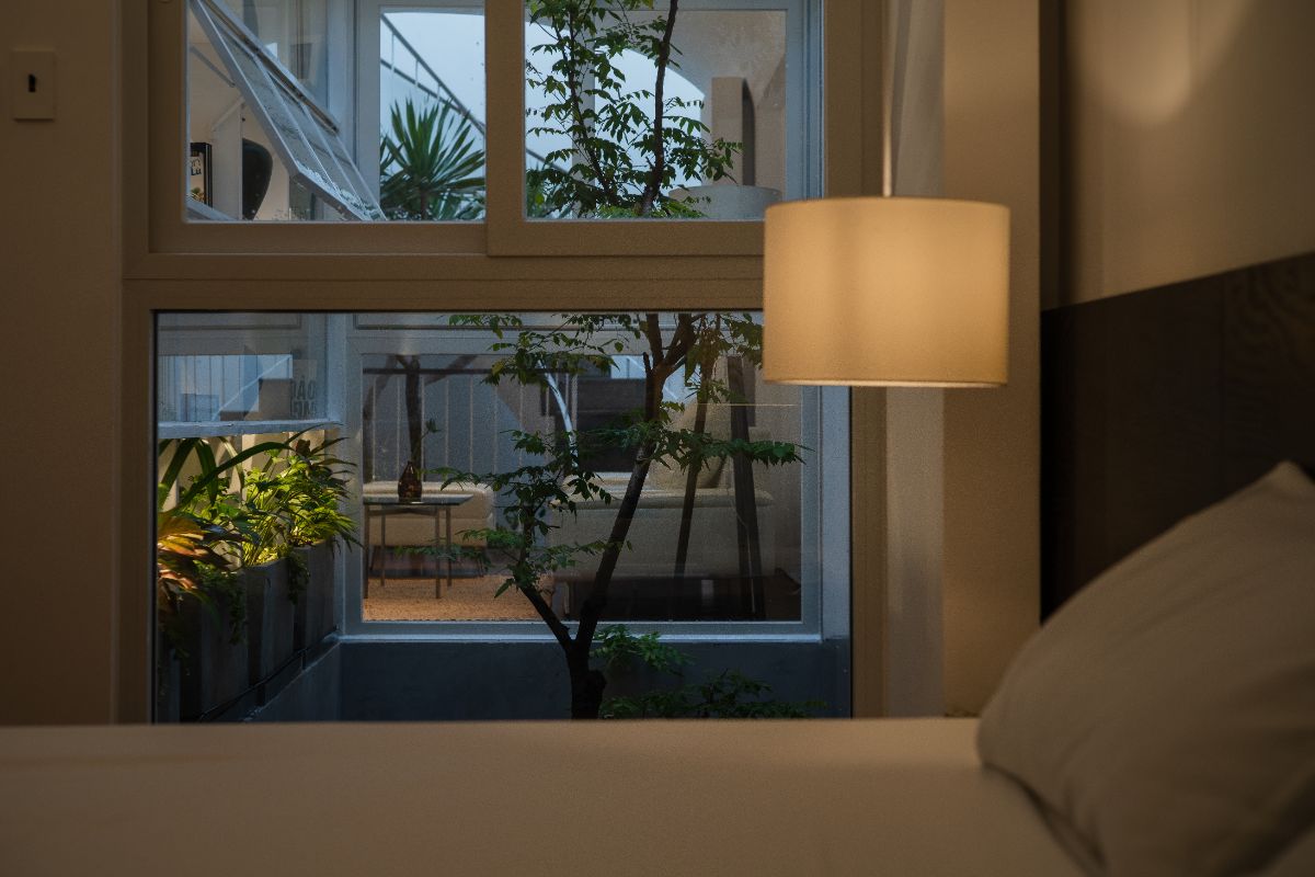 A bedroom with full length glass window facing the living space on the other side.