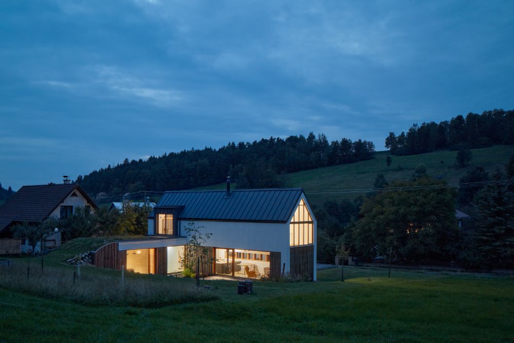 Wide full view of the house with slightly curve slope and lush greenery surround.