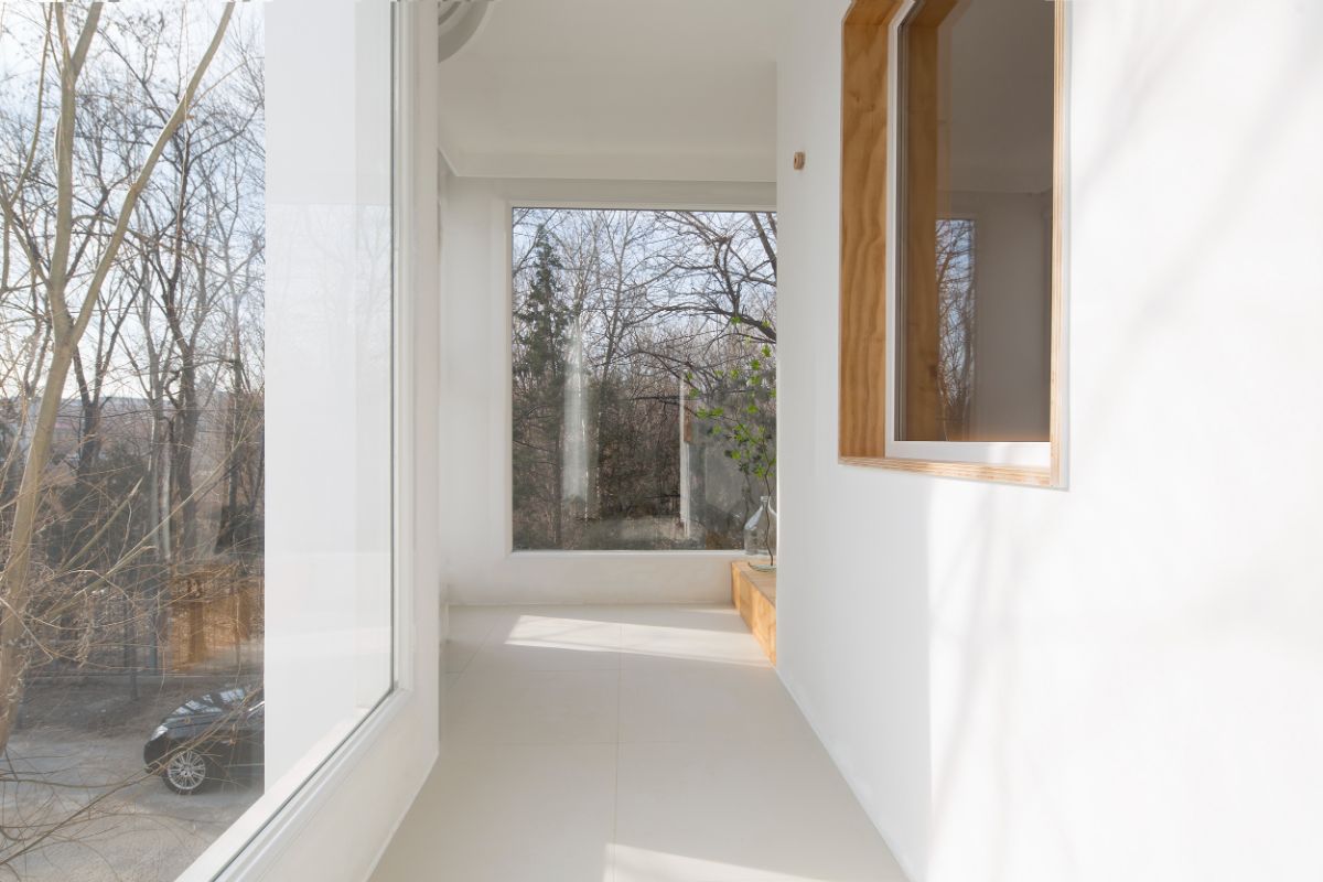 A hallway with large glass windows that leads to the guestroom.