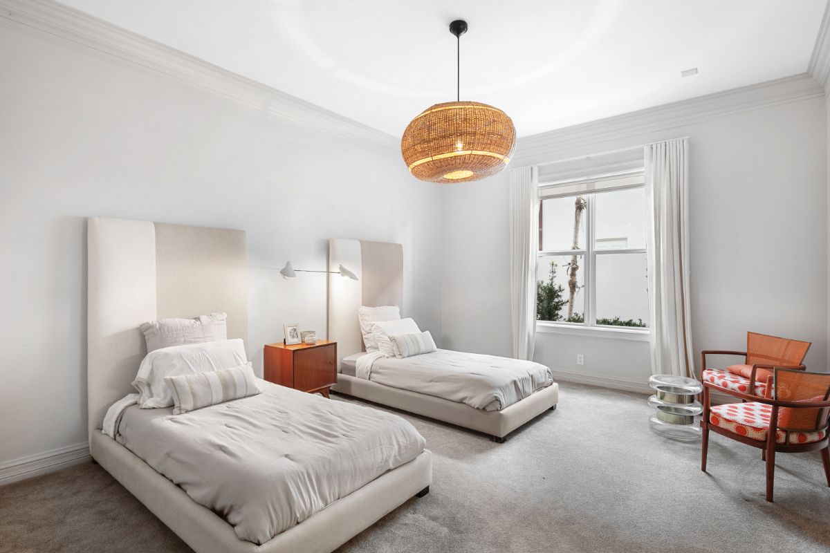 Guest room with two single beds and modern lighting.