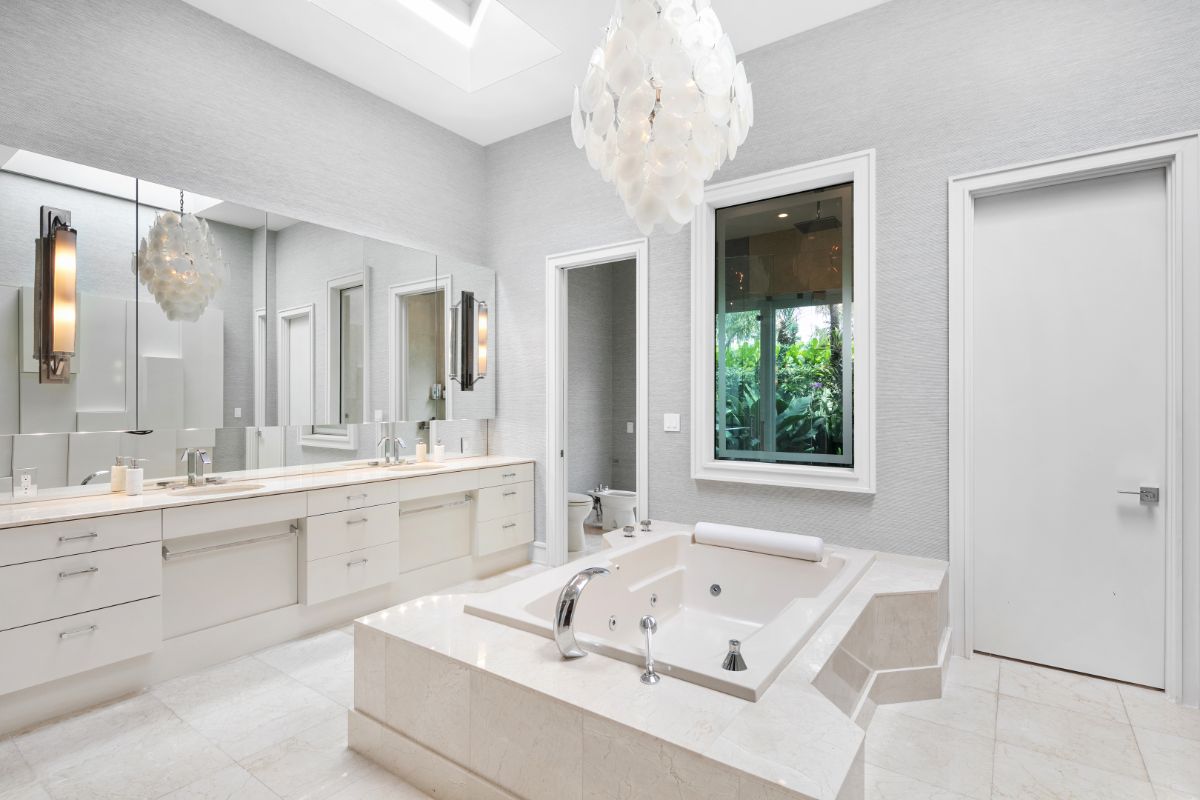 Modern master bathroom with built-in bathtub in center, full lenght mirror, and modern lighting.