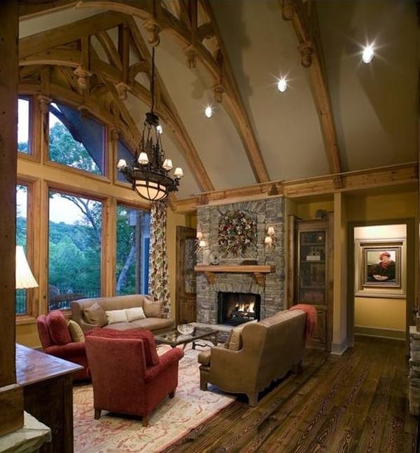 Lodge room with a stone fireplace, leather sofas, red armchairs, and a cathedral ceiling framed with exposed trusses.