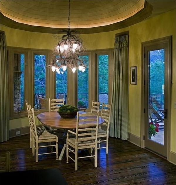 Lodge room with a stone fireplace, leather sofas, red armchairs, and a cathedral ceiling framed with exposed trusses.