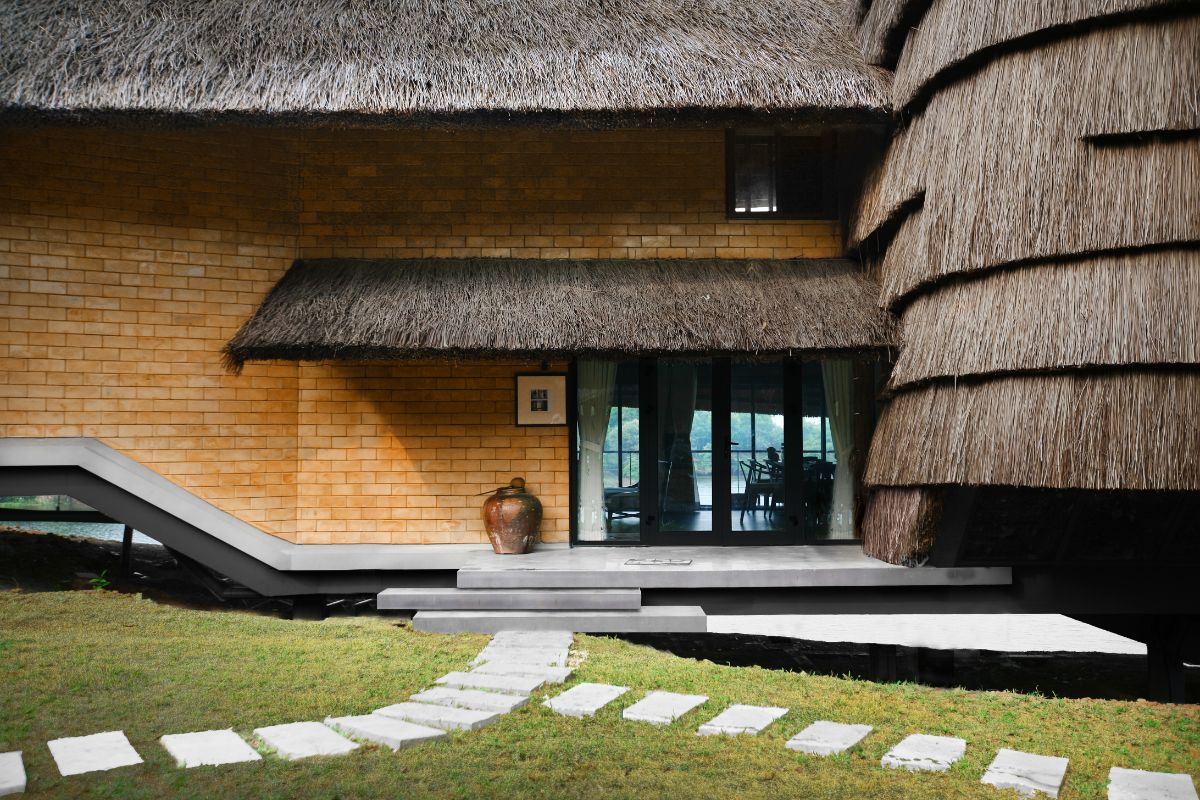 The main entrance, which features concrete walking paths, a thatched roof, and a brick wall.