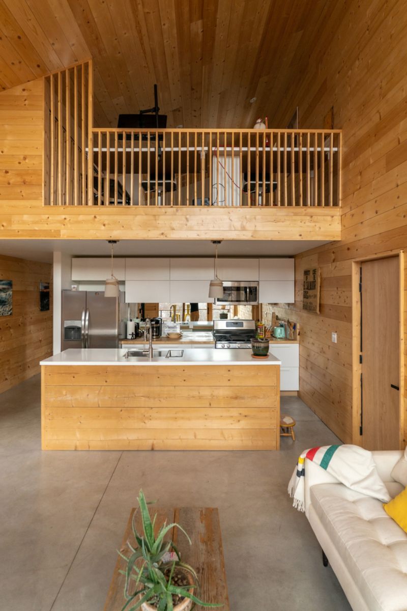 A double height living space connected to two level that features the kitchen and bedroom.