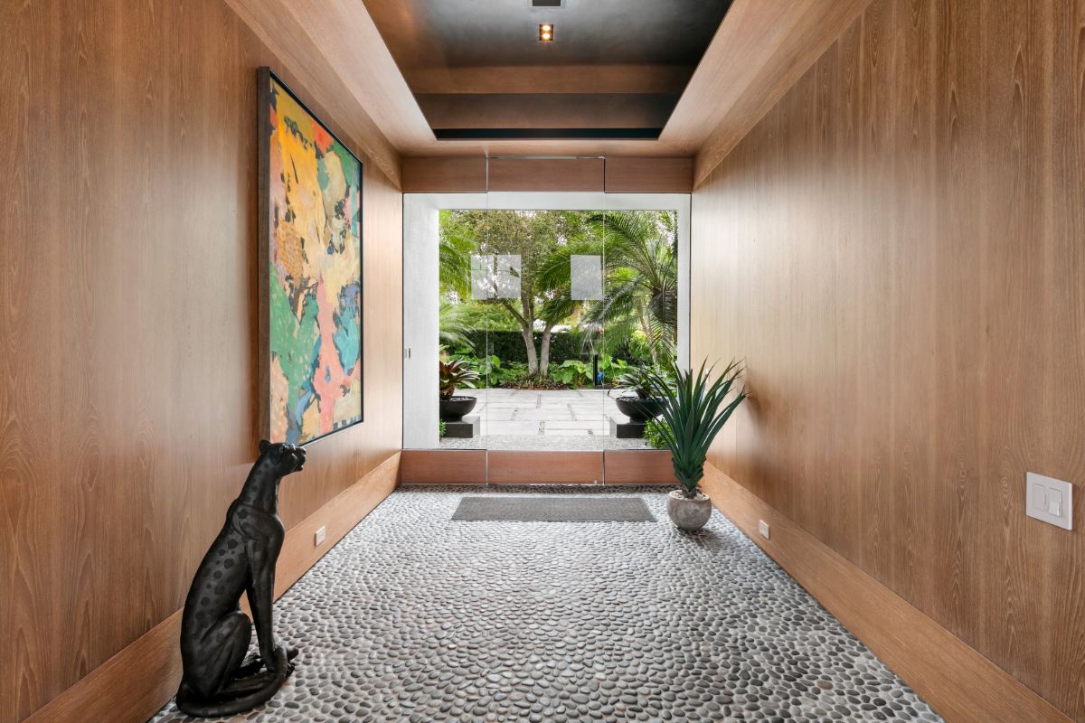 Main entrance in wooden wall, stone bricks flooring, and two way glass door.
