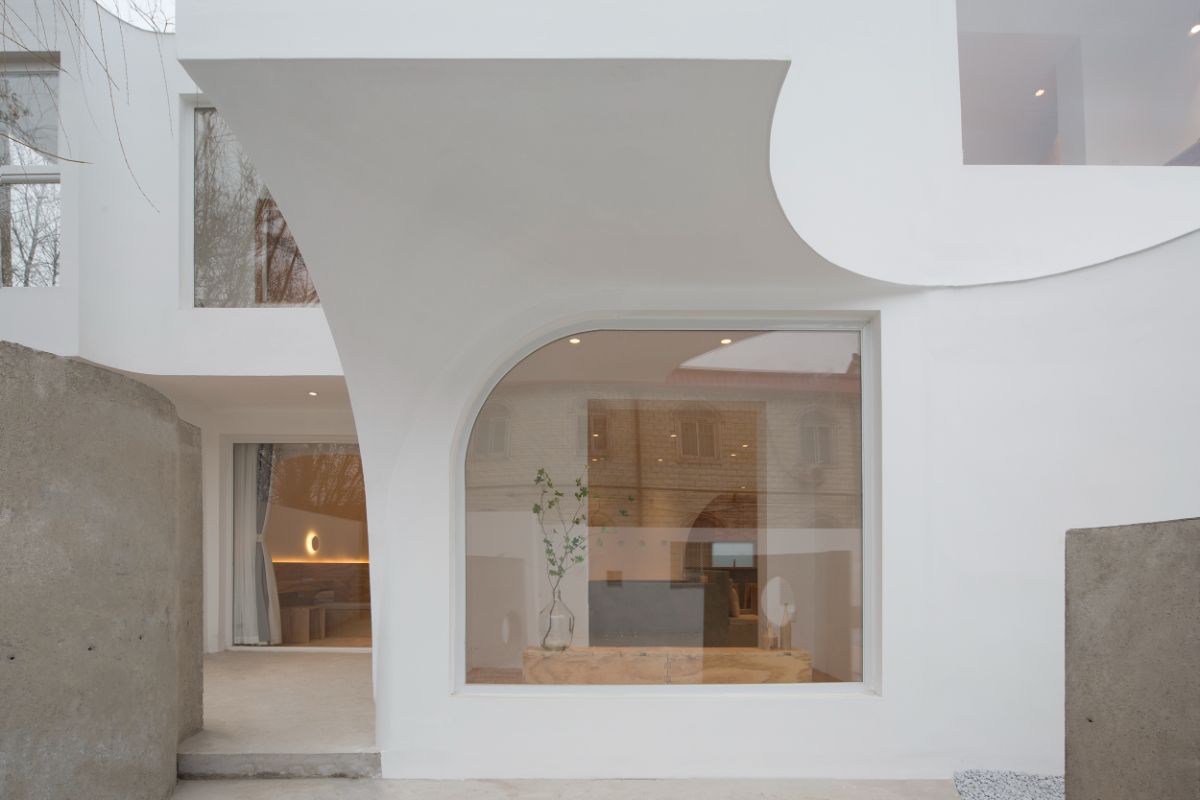 The large glass window in the shape of a quarter arc on the front facade of the house.