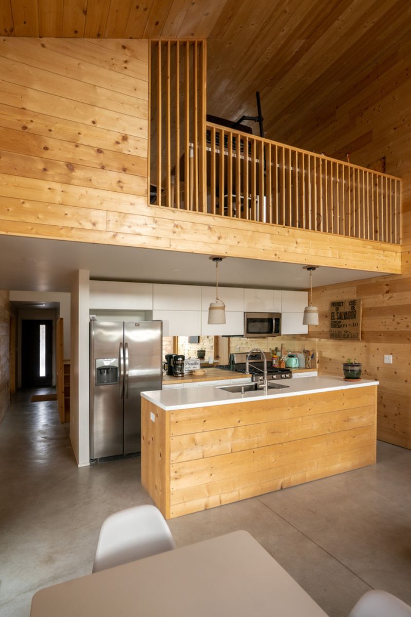 One horizontal view of the dining and kitchen that uses light wood materials.