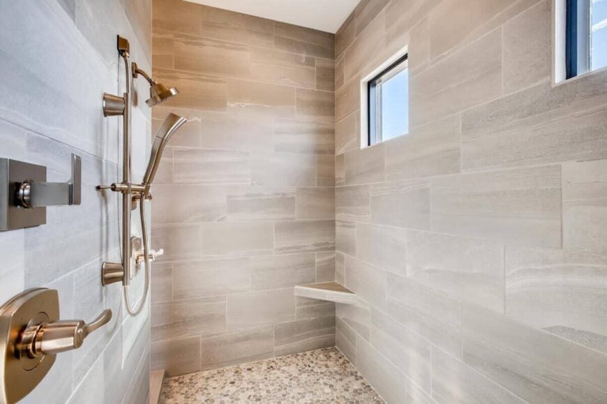 Walk-in shower with chrome fixtures, a corner bench, and small windows.
