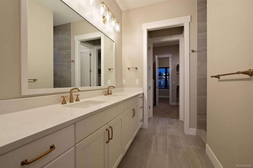This bathroom features a lengthy vanity with double sinks and a large framed mirror.