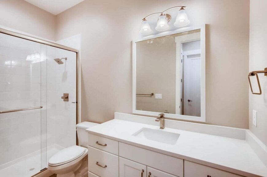 This bathroom is equipped with a sink vanity, a toilet, and a walk-in shower enclosed with sliding glass doors.