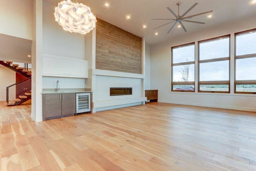 Great room with a modern fireplace, a wet bar, and an industrial ceiling fan.