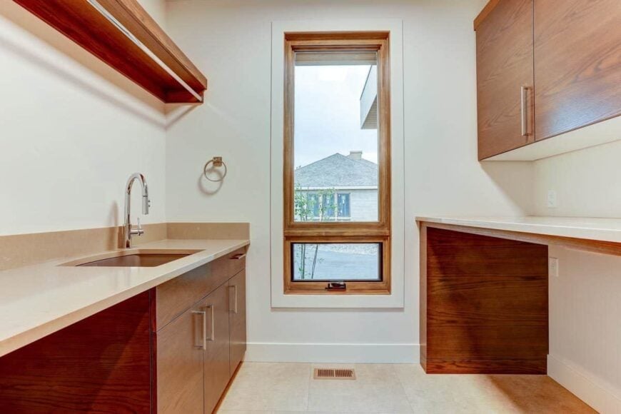 The laundry room is equipped with wooden cabinets, quartz countertops, and a utility sink.