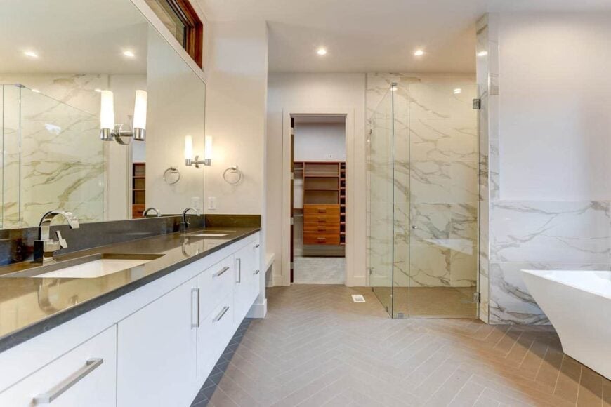 Primary bathroom with a dual sink vanity, a shower area, freestanding tub, and a walk-in closet.