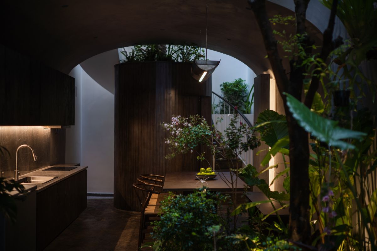 A ground floor kitchen area covered with full concrete surface with wooden tables and cabinets and marble-topped sink.