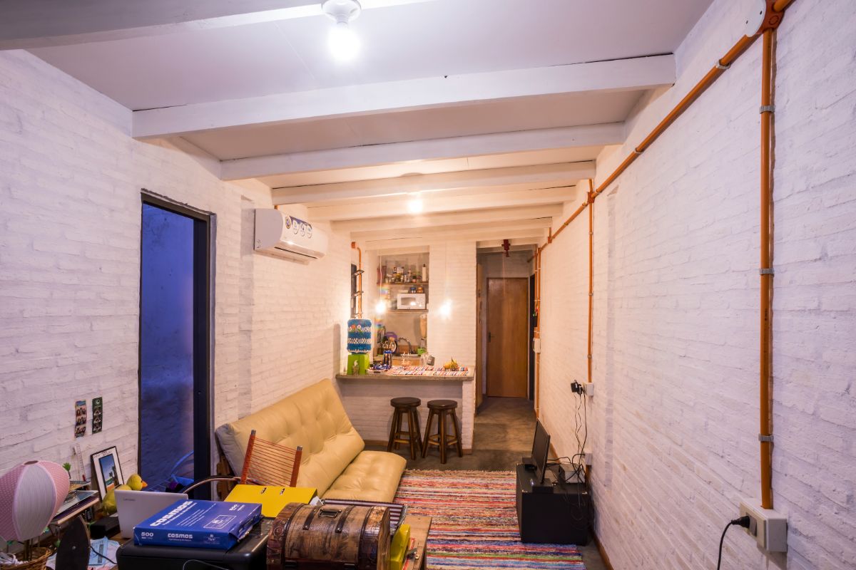 A living room with a white painted brick wall and a shed-beamed ceiling.