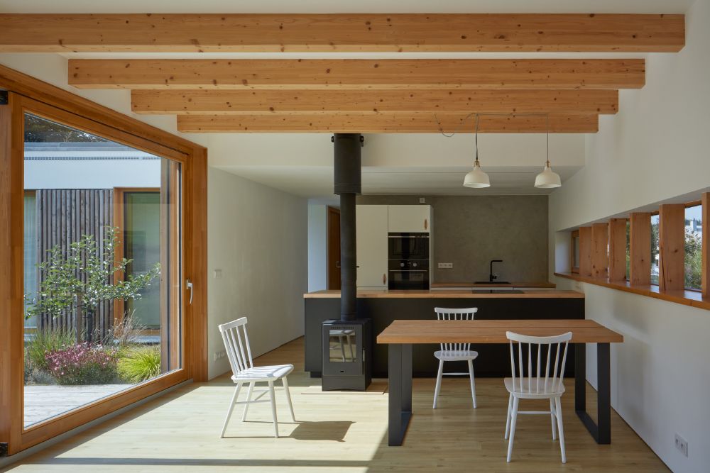 Dining area connected to kitchen with glass wall, beamed ceiling and self contained steel fireplace.
