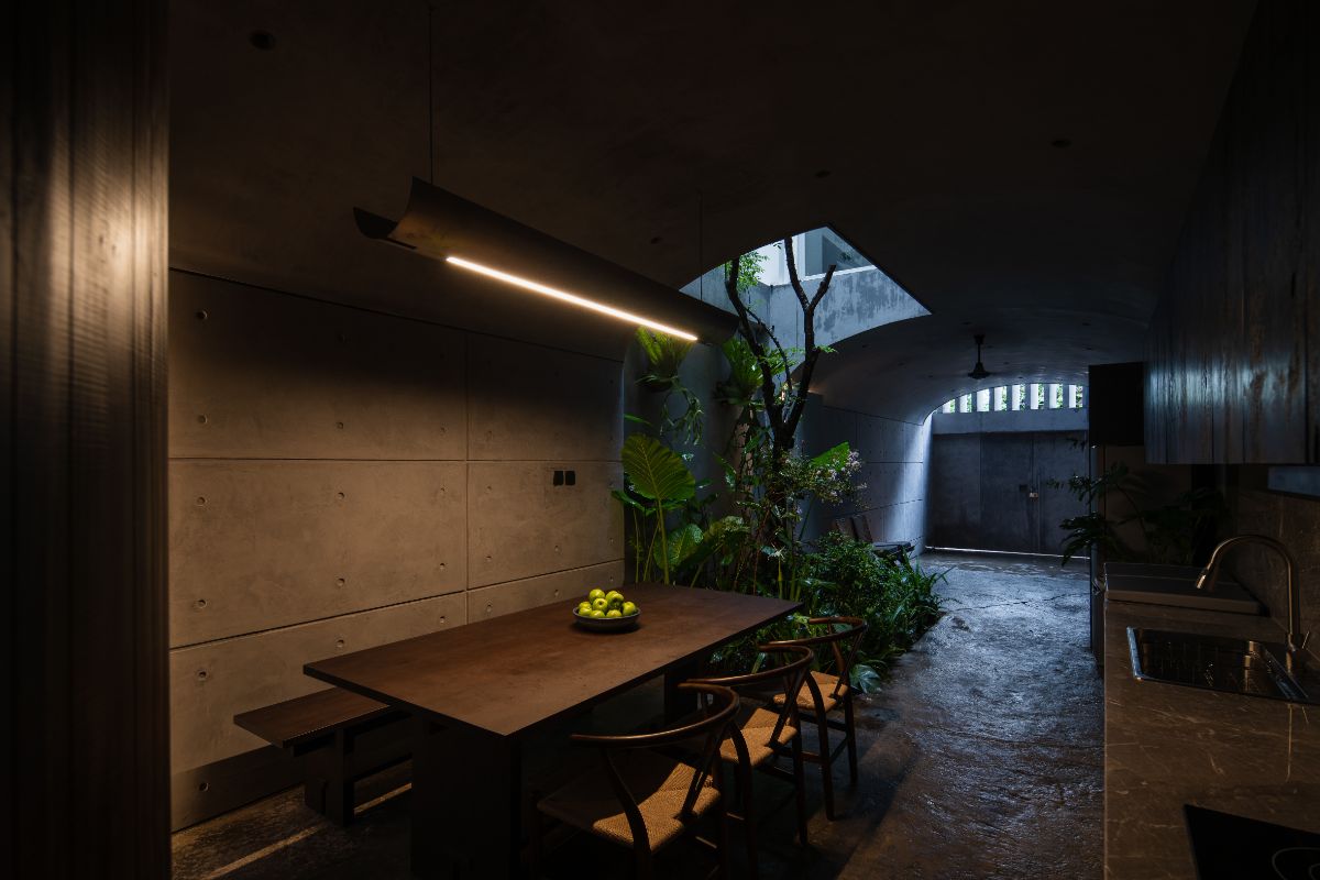 A ground floor kitchen area covered with full concrete surface with wooden tables and cabinets and marble-topped sink.