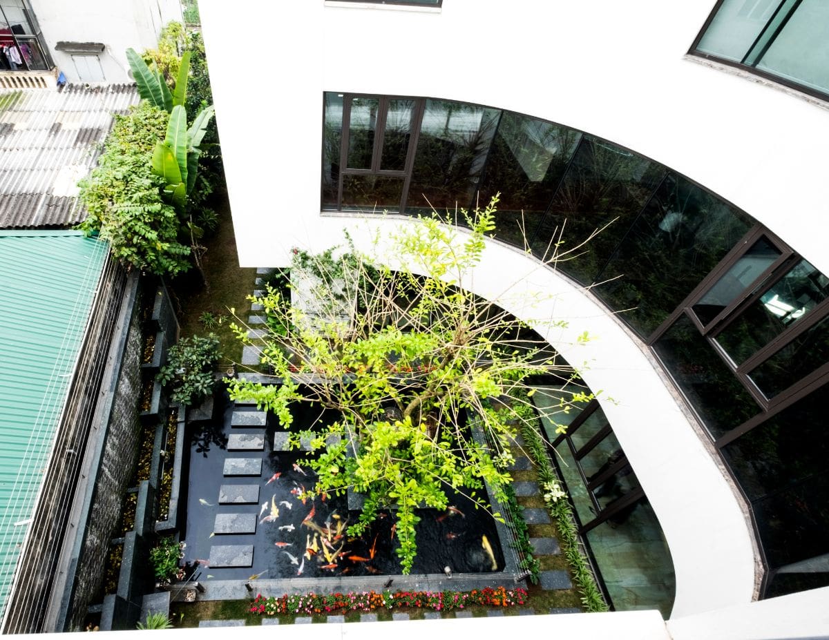 An aerial view of the house shows the open space in the center, which is highlighted by the pond and vegetation.