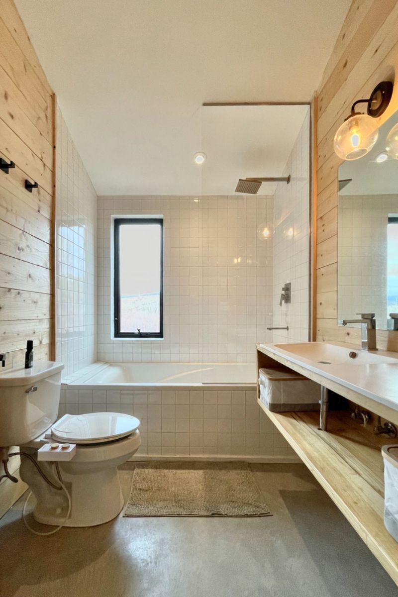 The bathroom with built-in alcove bathtub and wooden surface.
