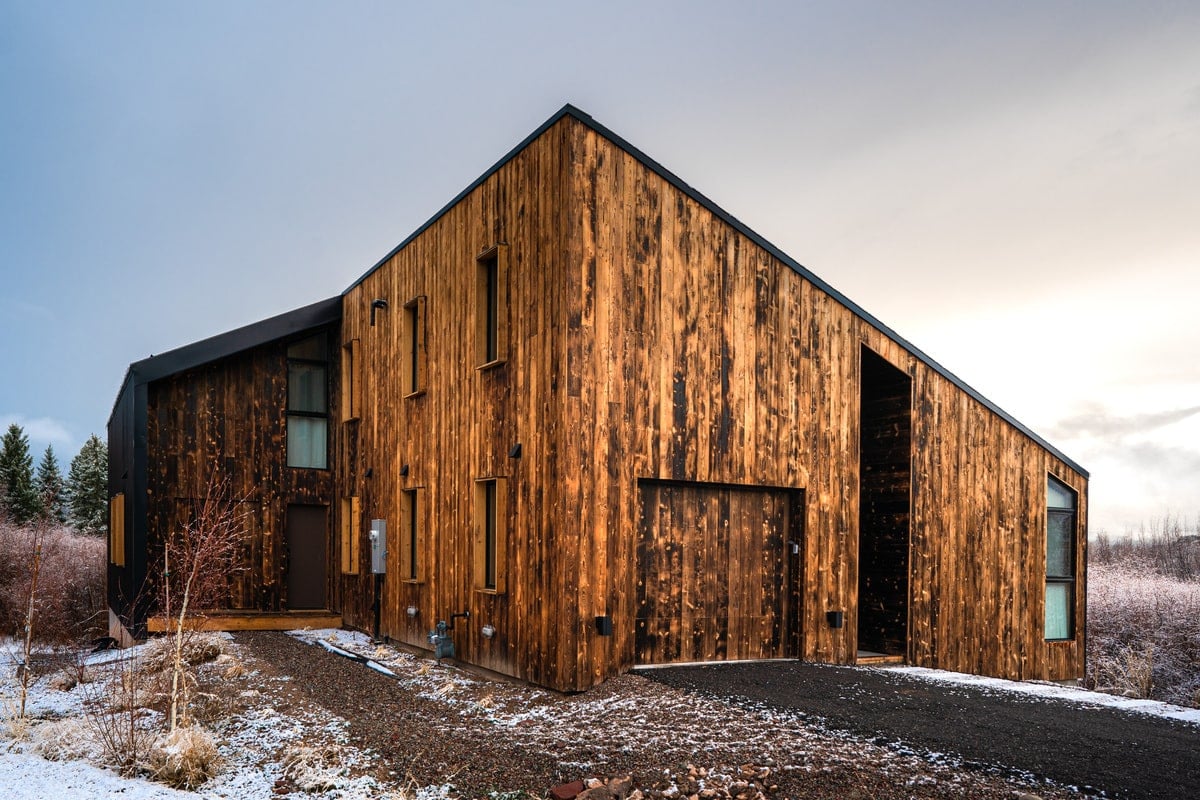 The exterior of the house in finished wood surface and wide glass windows.