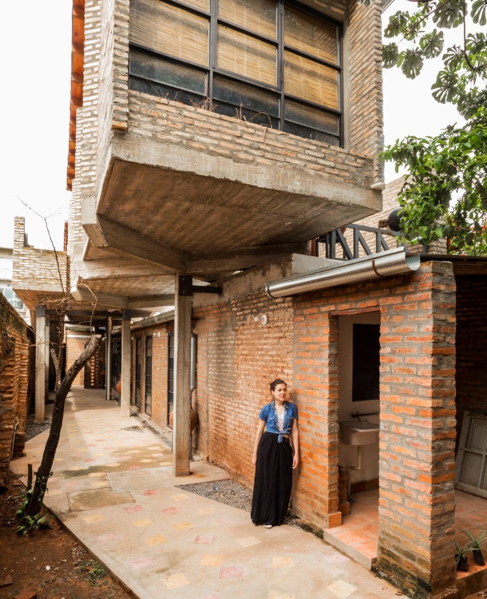 A woman stands in the back yard of the house.