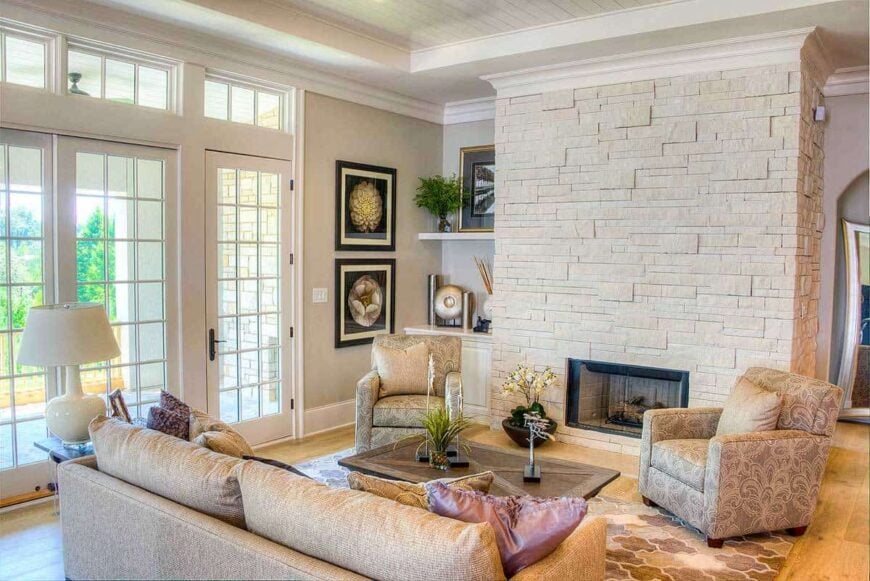 The living room has beige seats, a brick fireplace, and a glazed door that opens to a covered porch.
