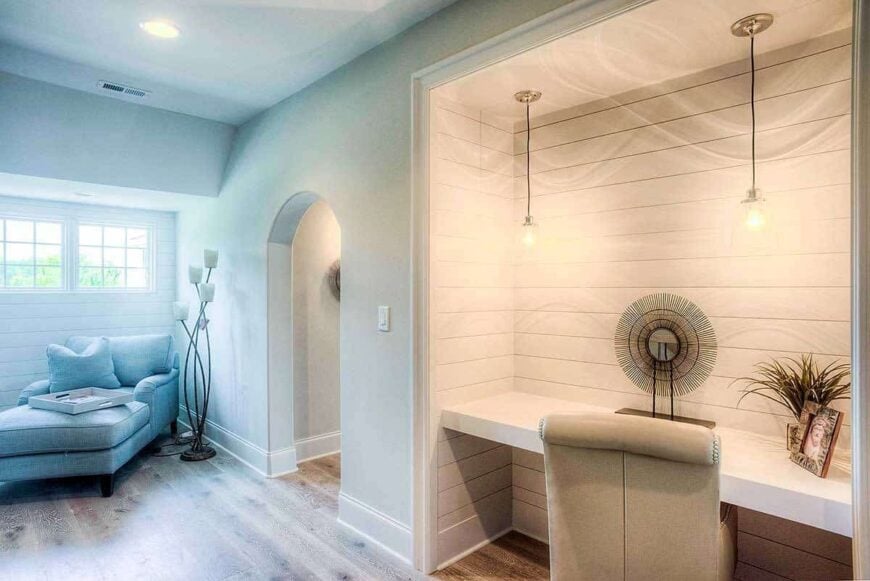 Study nook with a built-in desk and a sitting area by the white-framed windows.