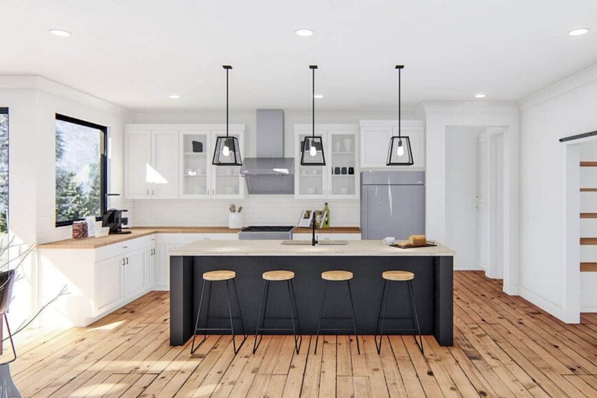 Kitchen with slate appliances, white cabinetry, and a wood-top island lined with round bar stools.