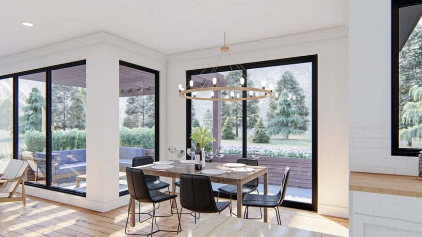 Bright dining area with black contemporary chairs and a wooden dining table topped with a round chandelier.